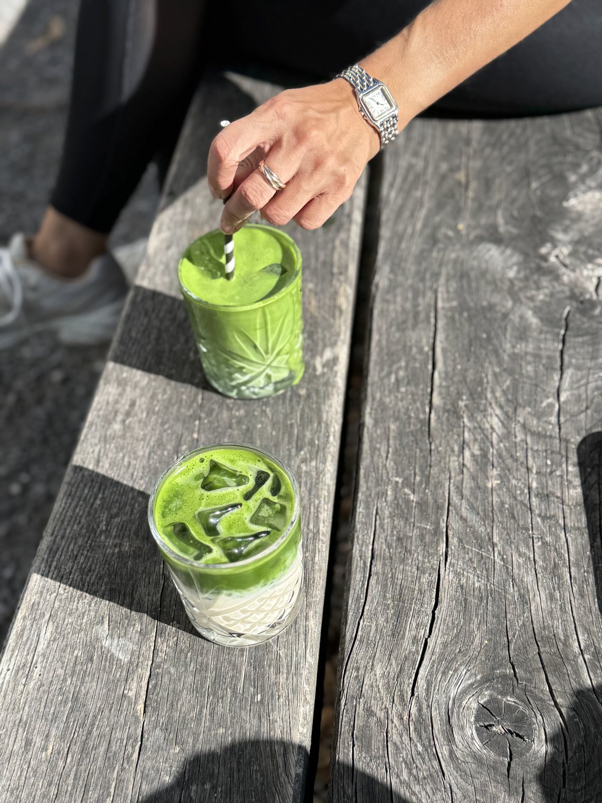Zwei Gläser Iced Matcha auf einer Holzbank